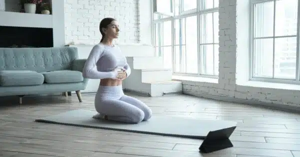 Žena na podložke precvičuje dýchanie pri joge